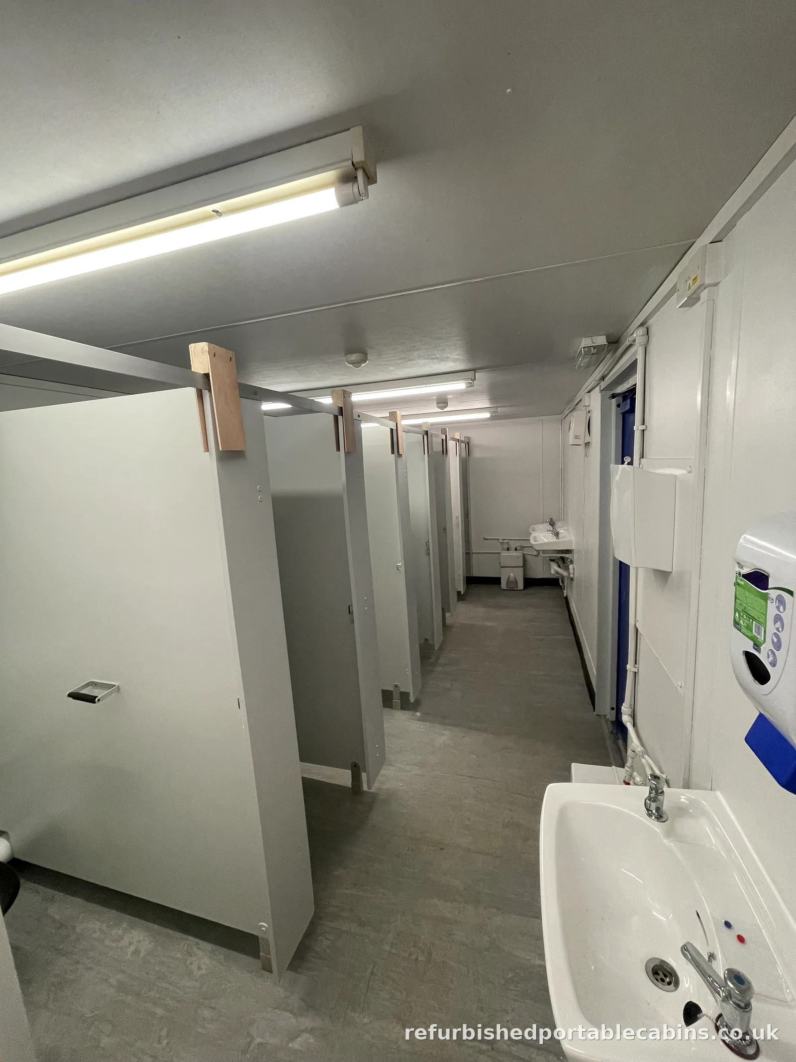 Refurbished toilet block with a row of cubicles and wash basins