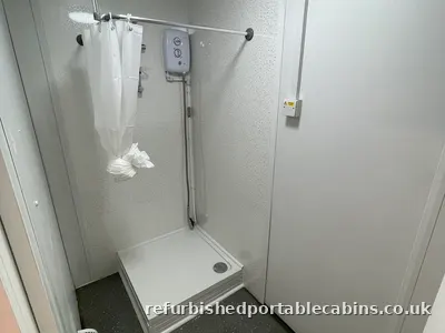 Shower tray, curtain rail and electric shower fitted in a refurbished portable cabin